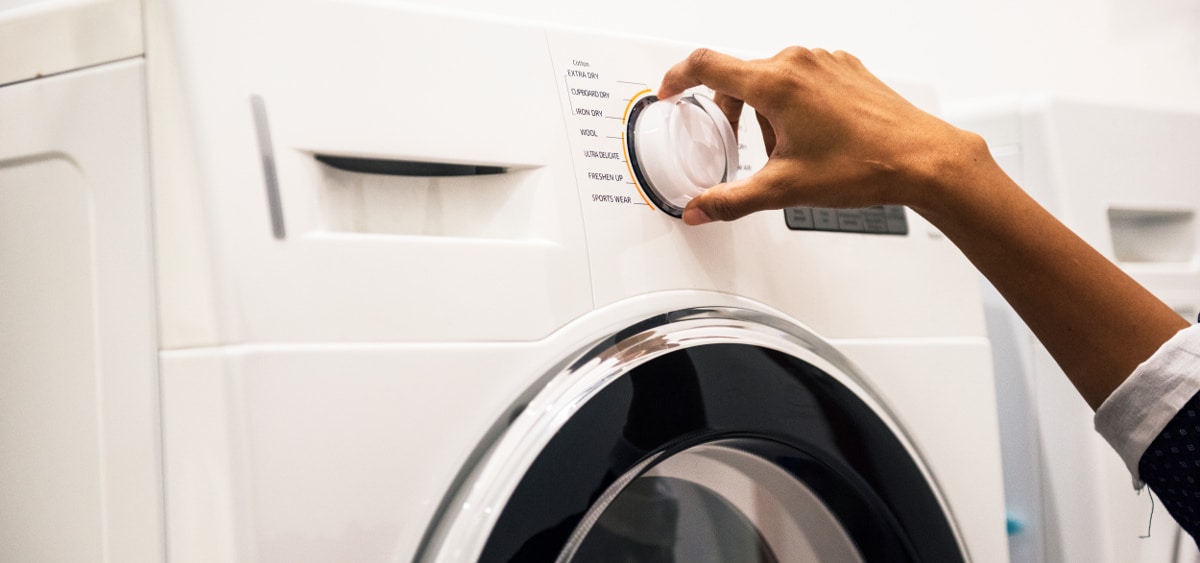Nærbilde av en hånd som stiller inn vaskemaskinen